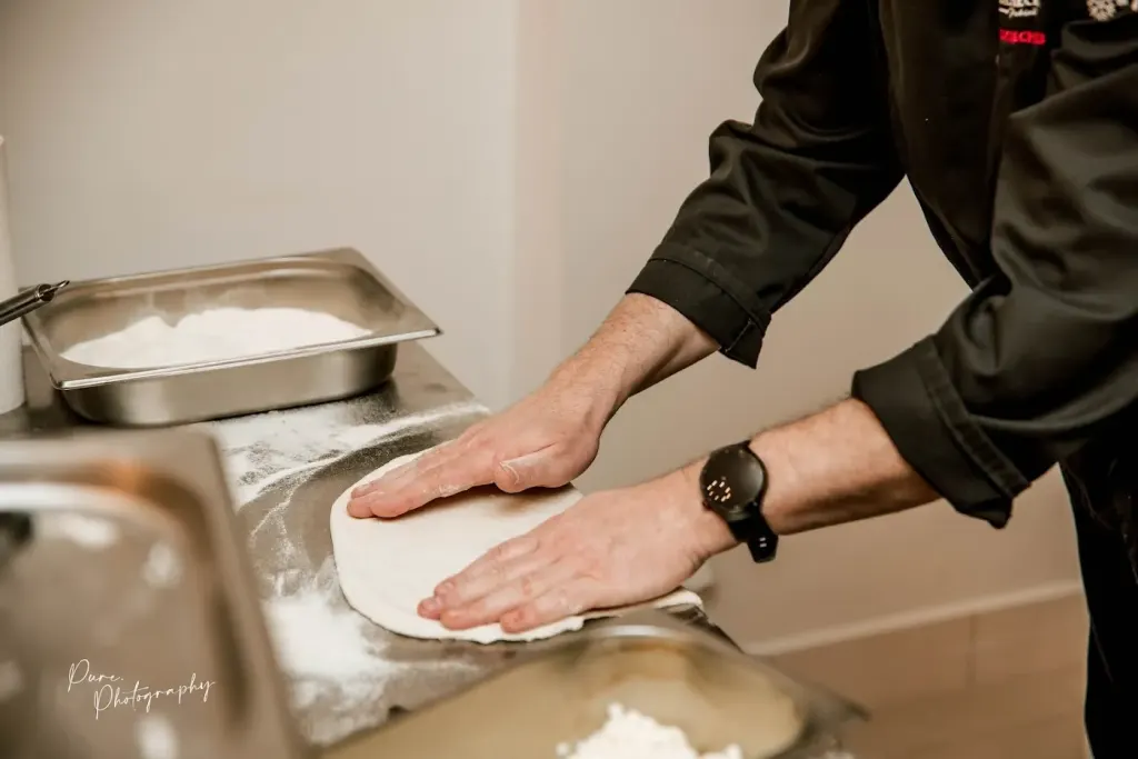 Kucharz rozciągający ciasto na pizzę